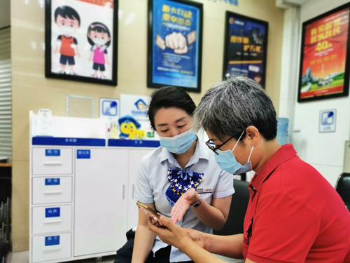 建行成都第六支行，大堂經理為客戶介紹手機銀行&ldquo;大字&rdquo;模式